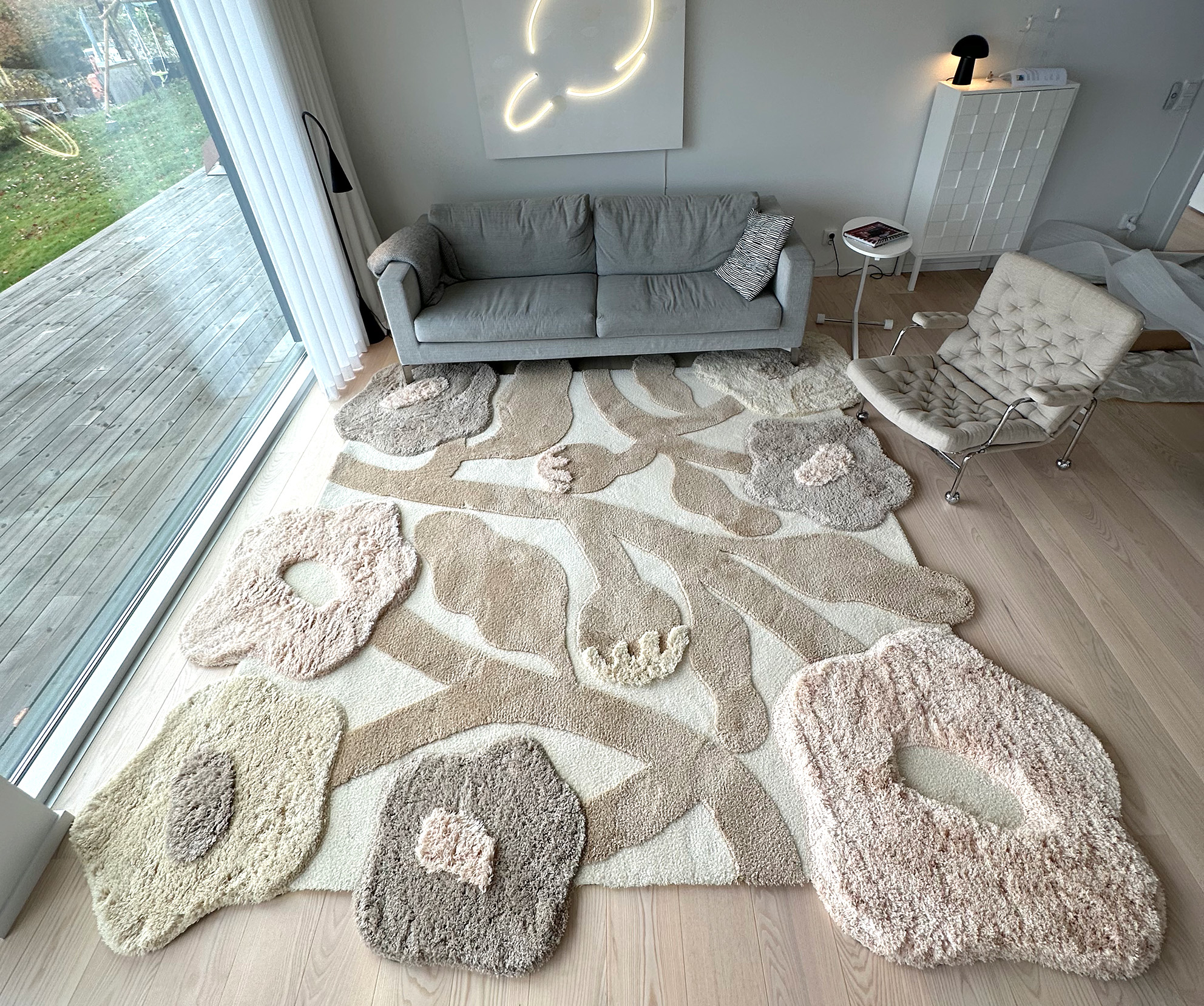 Creamy colored big poppy rug in living room with art